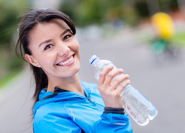 Woman hydrating after workout drinking water from a bottle